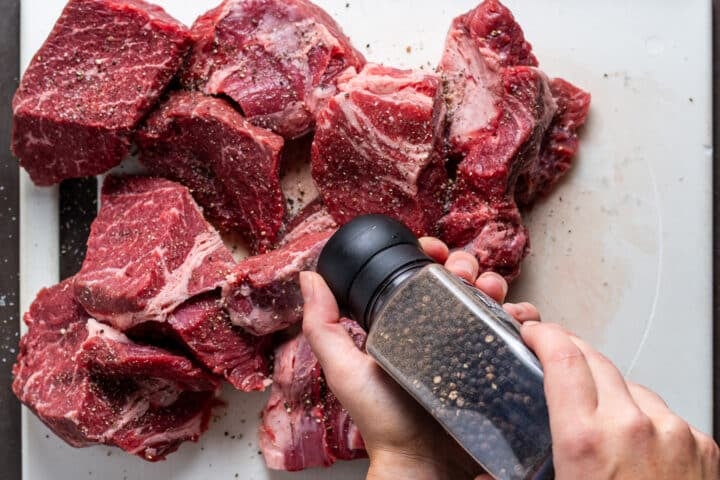 hands using a pepper grinder to season the meat