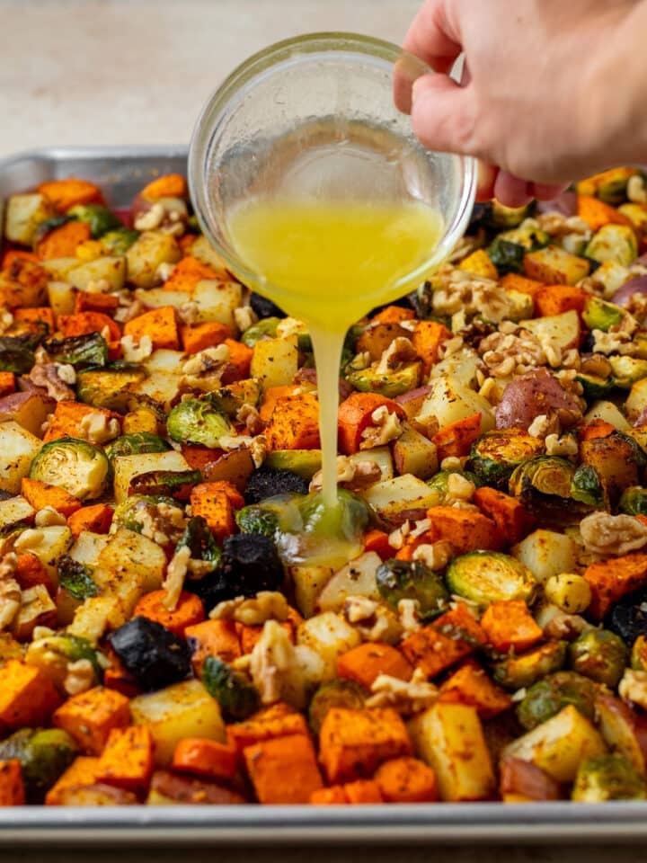 hand pouring a honey butter glaze on roasted vegetables