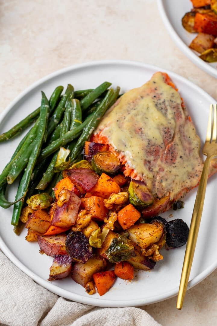 white plate with glazed salmon, lemon green beans and honey roasted vegetables