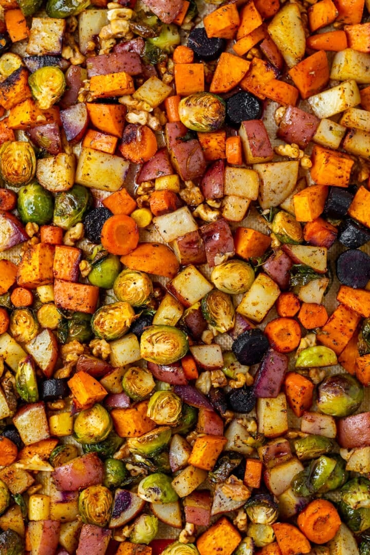 sweet potatoes, carrots, red potato, brussels sprouts and walnuts on a sheet pan with honey butter glaze