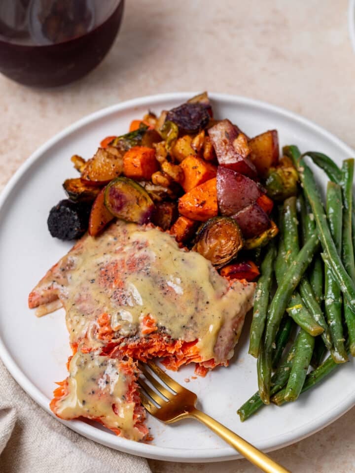 gold fork taking a bite out of a piece of maple dijon glazed salmon