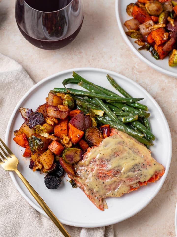 portion of maple dijon salmon on a plate with roasted vegetables and lemony green beans