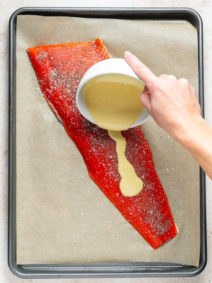 hand pouring glaze out of the bowl and onto the salmon