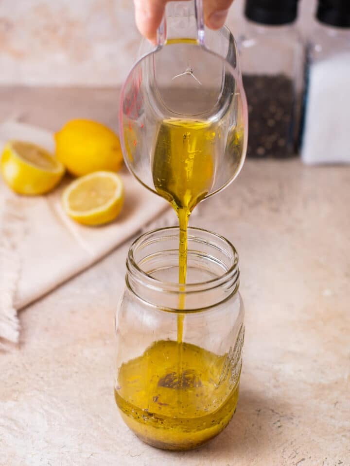 pouring olive oil into a mason jar with other dressing ingredients