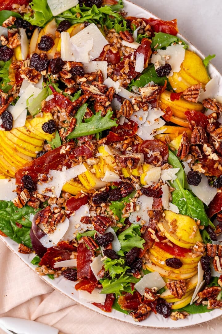close up view of a pear and pecan salad with farro, parmesan cheese and dried cherries