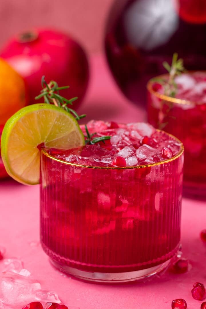 small tumbler glass filled with ice, pomegranate punch and pomegranate arils
