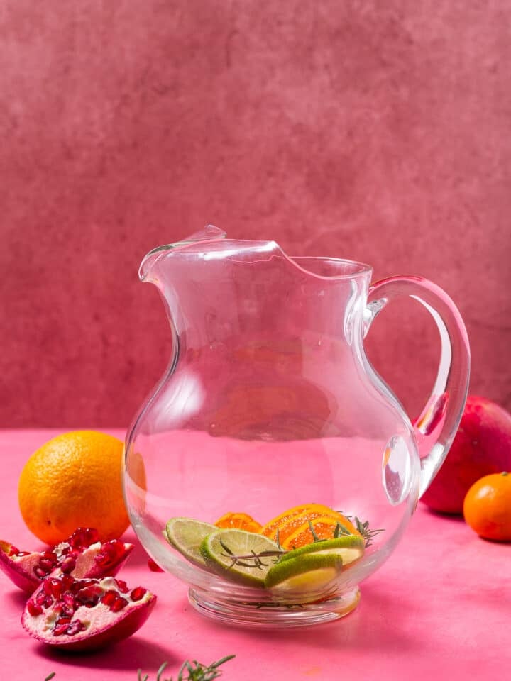 glass pitcher with lime slices, orange slices and fresh rosemary