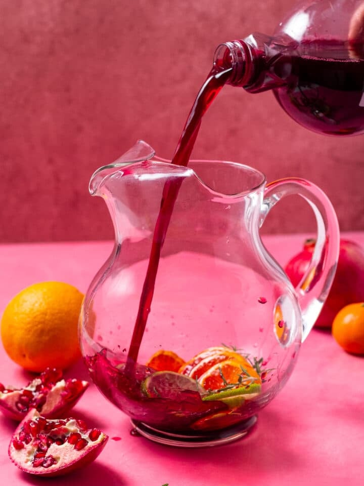 pouring pomegranate juice in a glass pitcher