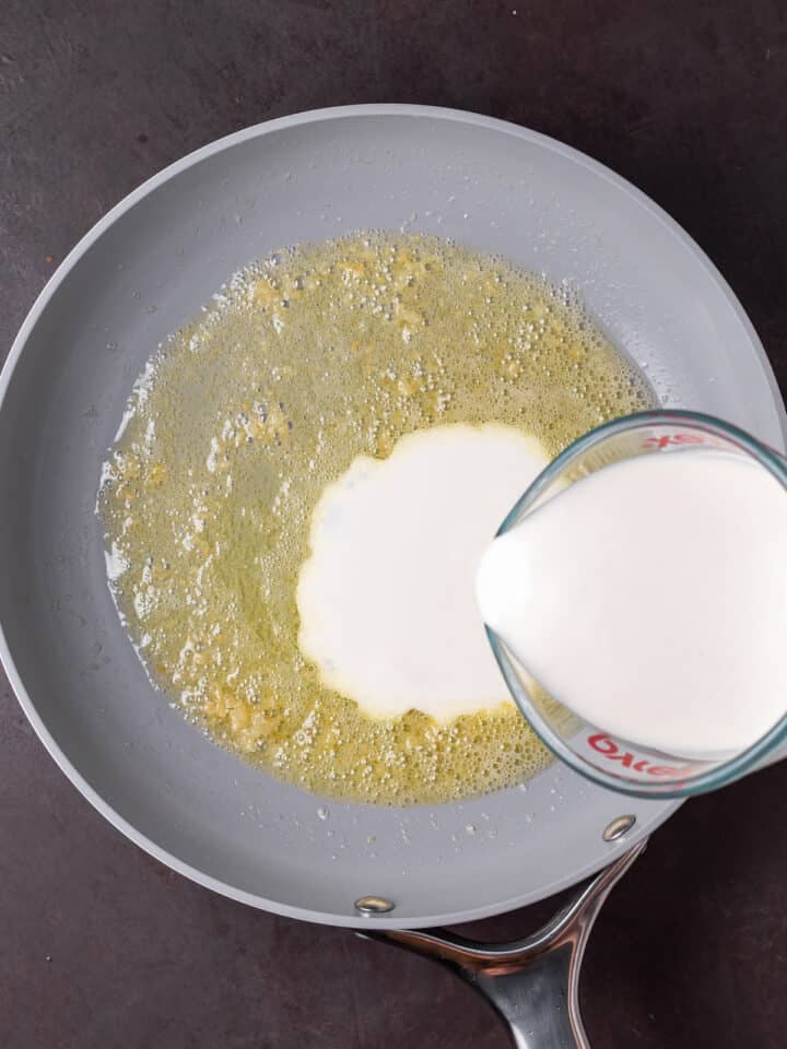 pouring heavy cream into melted butter and garlic in a skillet