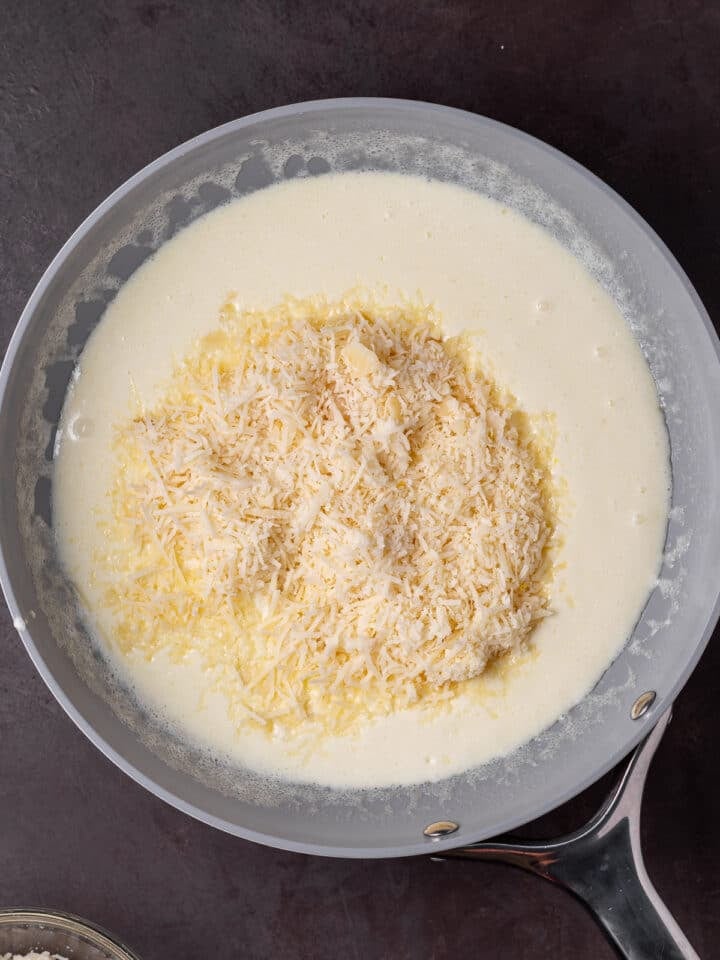 grated parmesan cheese added to heavy cream mixture in skillet