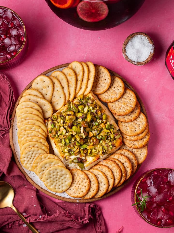 baked feta appetizer with pistachios and hot honey, surrounded by crackers