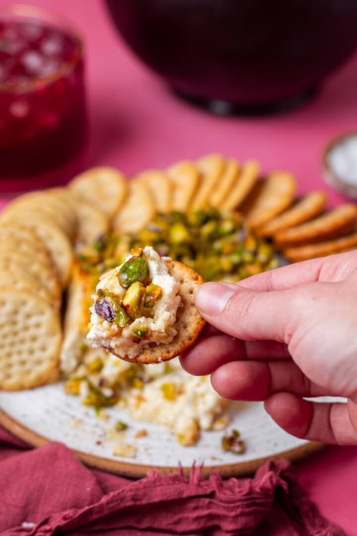 hand holding a portion of baked feta appetizer on a cracker