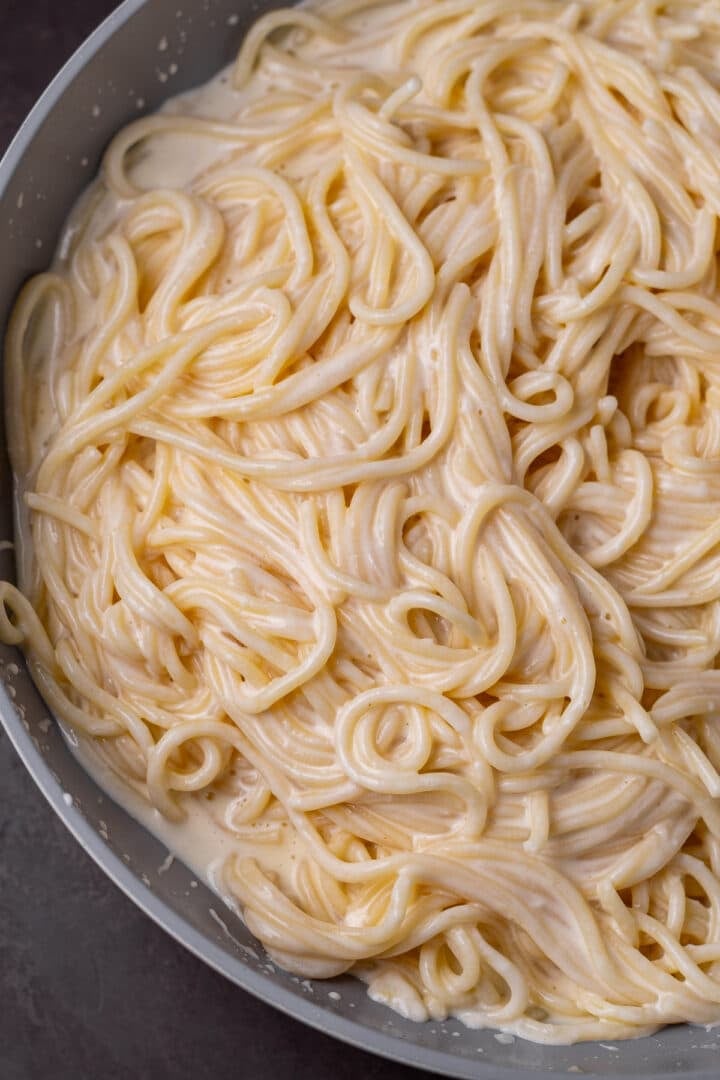 close up view of creamy spaghetti noodles in a skillet