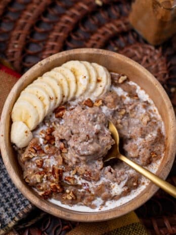 picture of caramelized date oatmeal on a golden spoon with banana slices and pecans