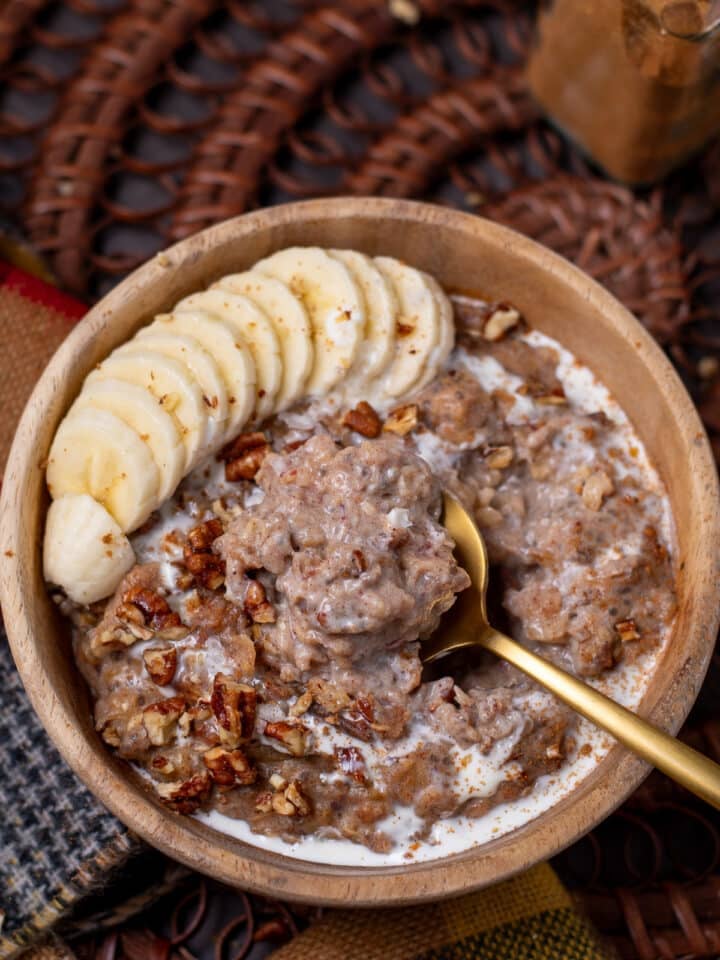caramelized date oatmeal on a gold spoon with pecans, cream and banana slices