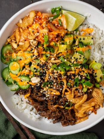 bowl with rice, shredded beef, kimchi, green onions, avocado and cucumber