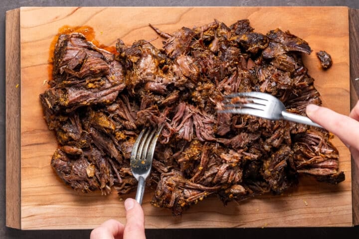 using two forks to shred cooked beef