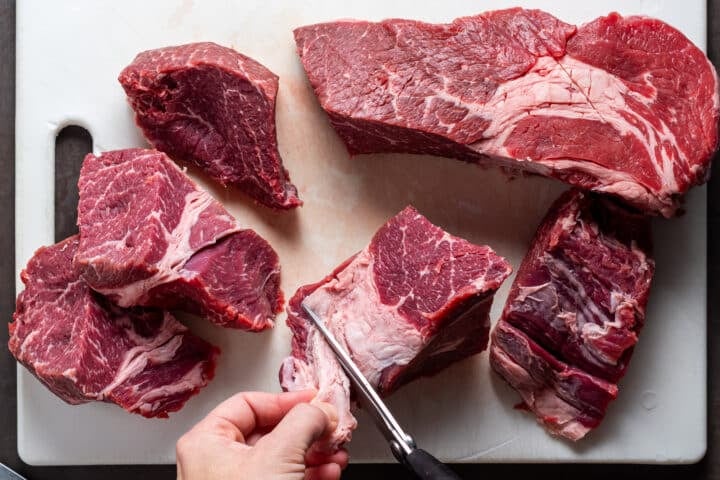 trimming away visible fat from beef chuck roast