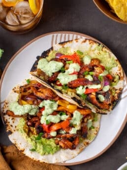 plate with two chicken fajitas with guacamole and cilantro yogurt sauce