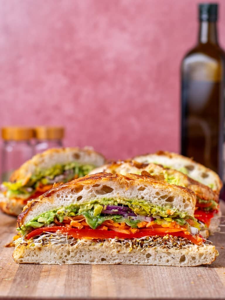 cross section where you can see the layers of colorful rainbow veggies in a sandwich