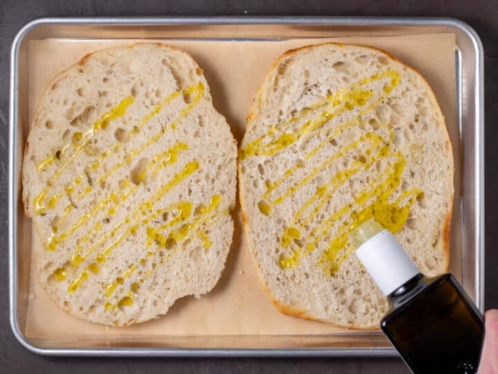 drizzling olive oil on cut halves of bread
