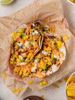 basket of two fish tacos with mango pico de gallow, cabbage and chipotle aioli