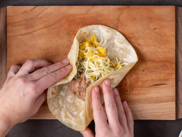 hands folding in the edges of a bean and rice burrito