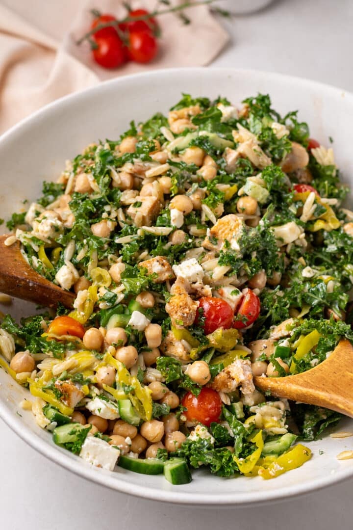 large white bowl with chicken and chickpea salad with tomatoes, kale, pepperoncinis, cucumbers and balsamic dressing