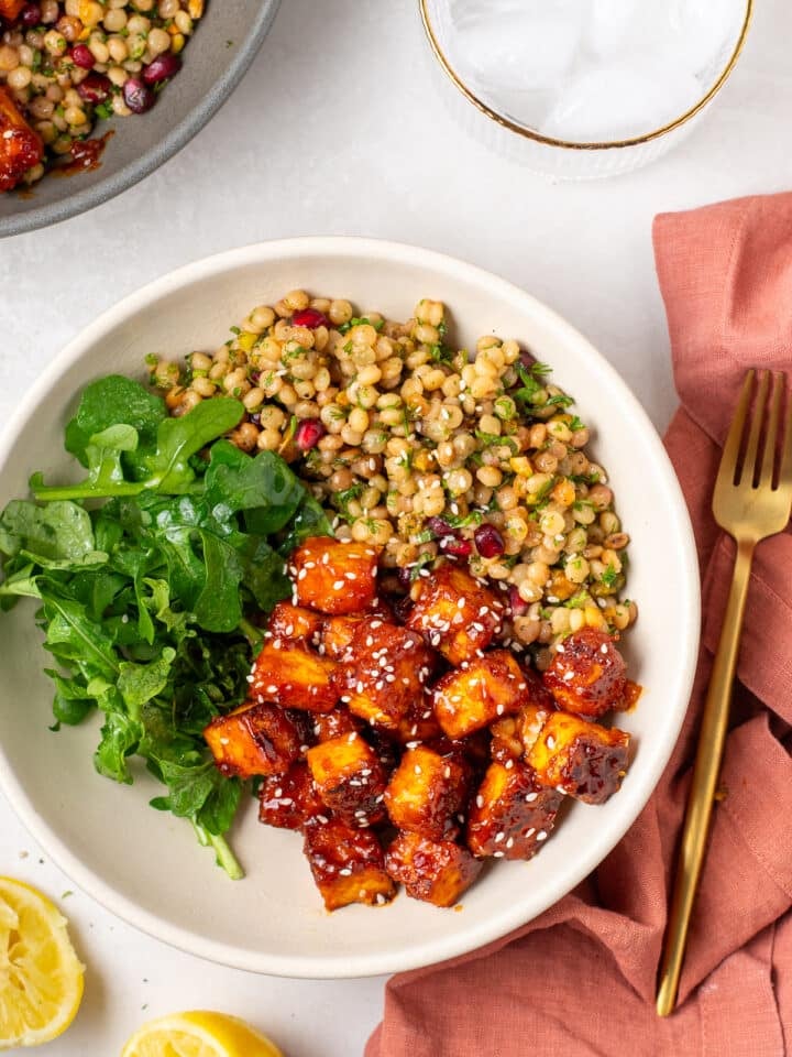 Bowl with harissa tofu, arugula and herby couscous pilaf with pistachios and pomegranate