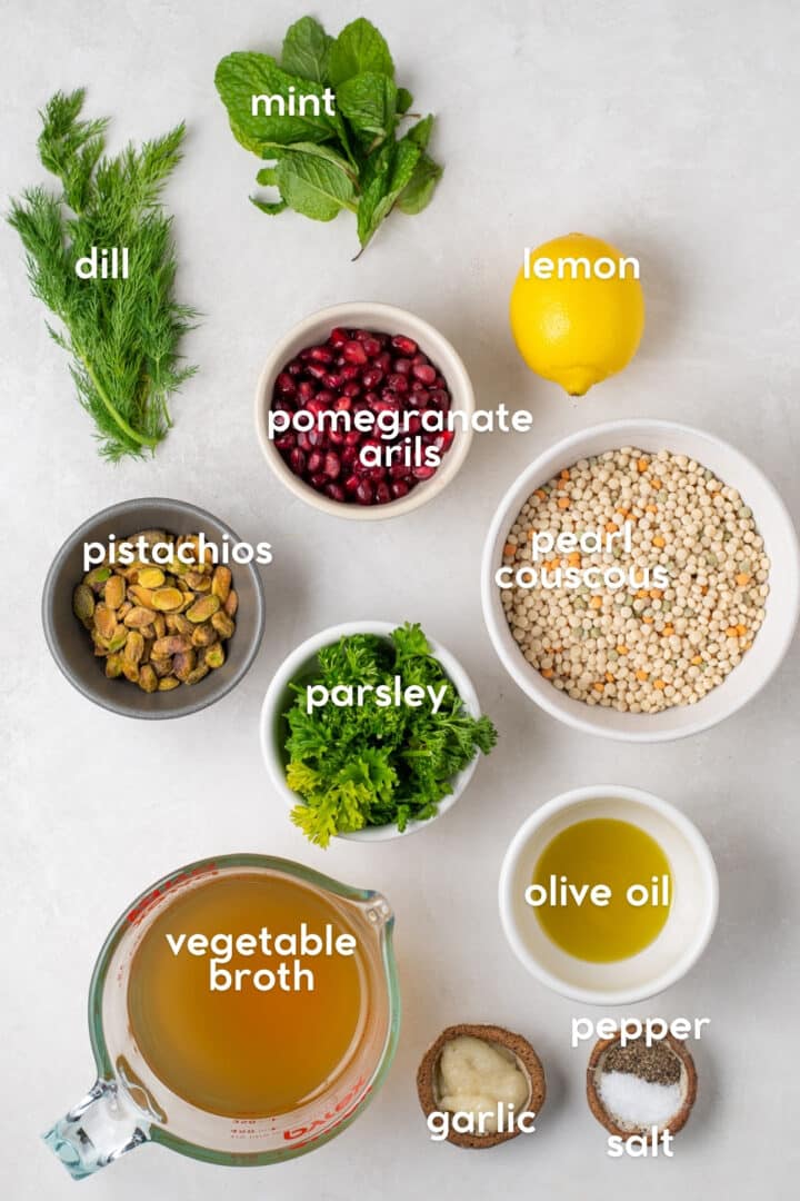 Ingredients for bright and herby couscous pilaf including pearl couscous, pistachios, pomegranate, lemon, parsley, dill, mint and broth