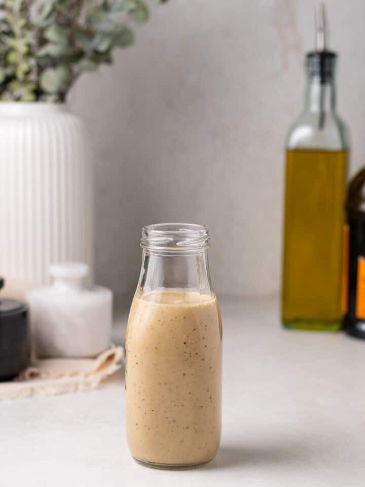 bottle of creamy balsamic dressing, tall bottle of olive oil, containers of salt and pepper