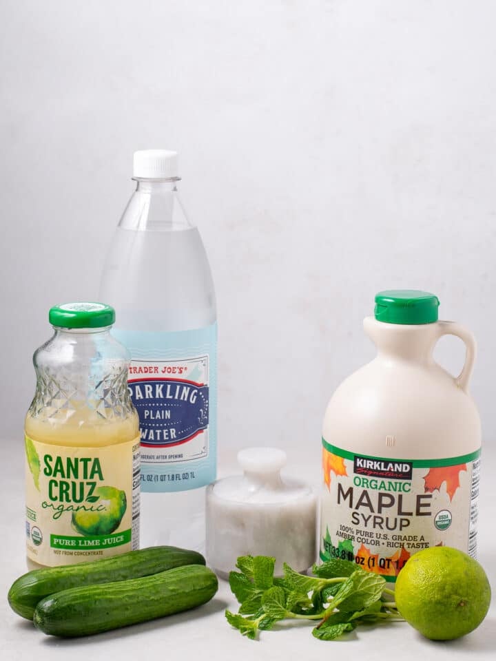 picture of sparkling water, lime juice, cucumbers, maple syrup, mint leaves and salt, all of the ingredients needed to make this mocktail