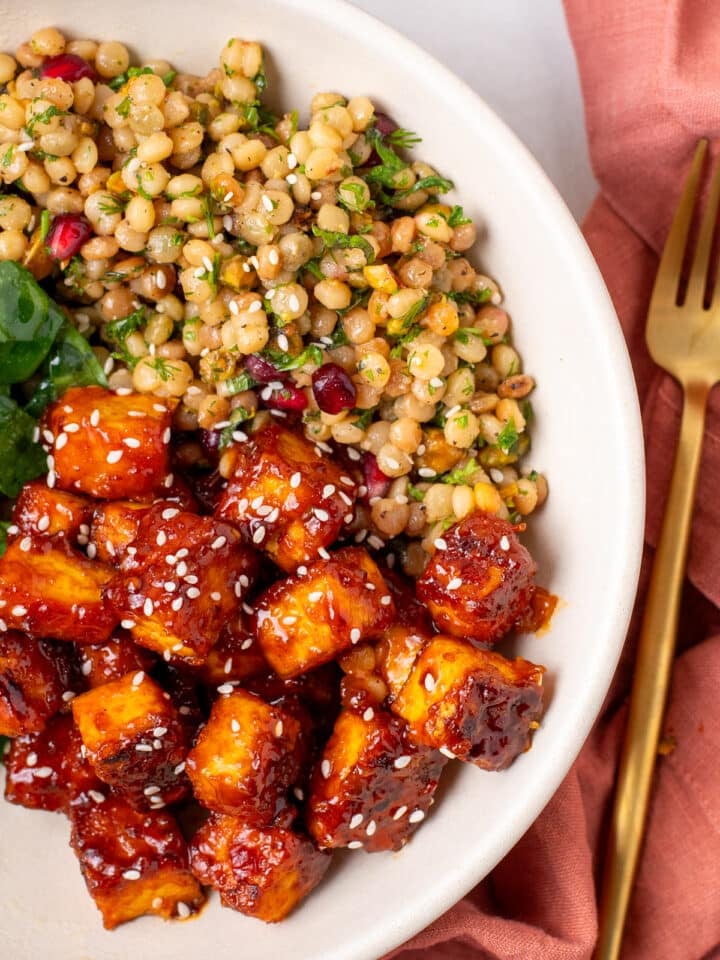 close-up of crispy harissa tofu cubes coated in sticky apricot harissa glaze