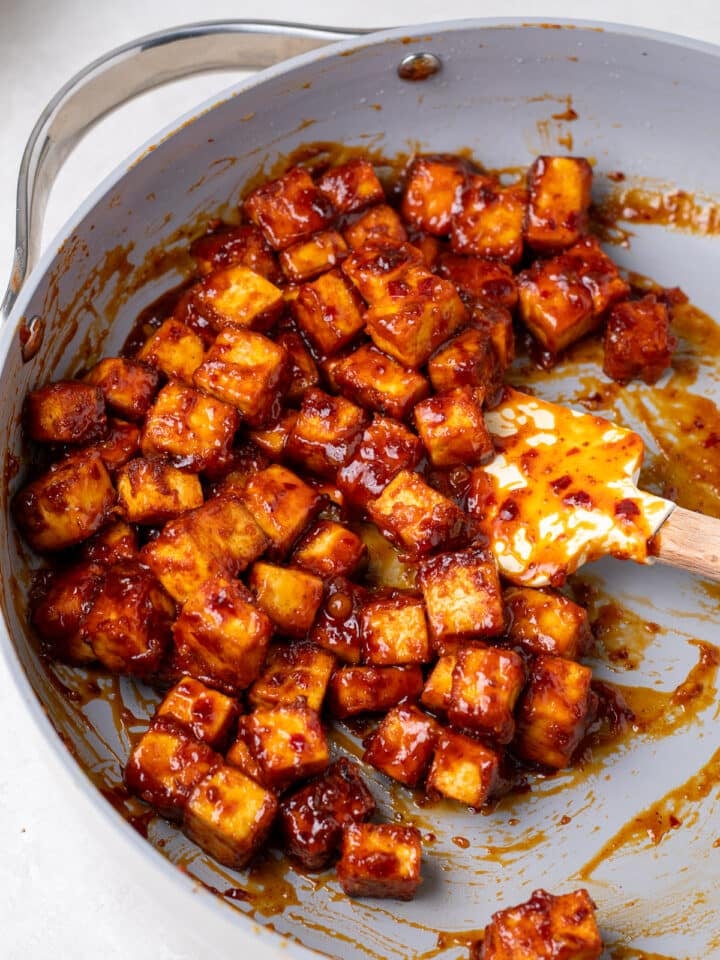 crispy tofu cubes coated in apricot harissa sauce in a skillet