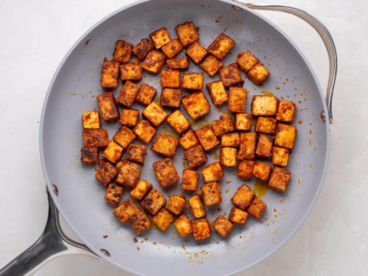 crispy tofu cubes browning in a skillet for apricot harissa tofu