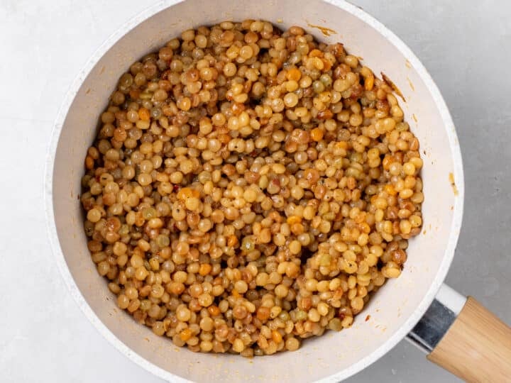 Cooked pearl couscous pilaf in skillet after simmering in vegetable broth