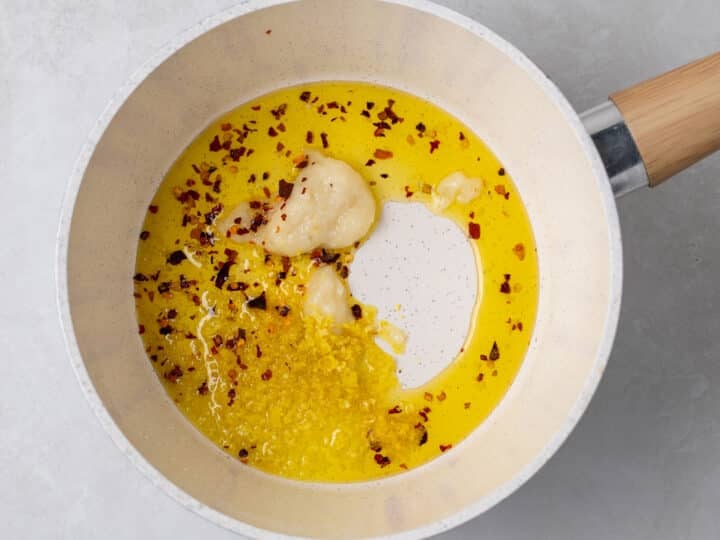 Olive oil, garlic paste, lemon zest and red pepper flakes cooking in a saucepan