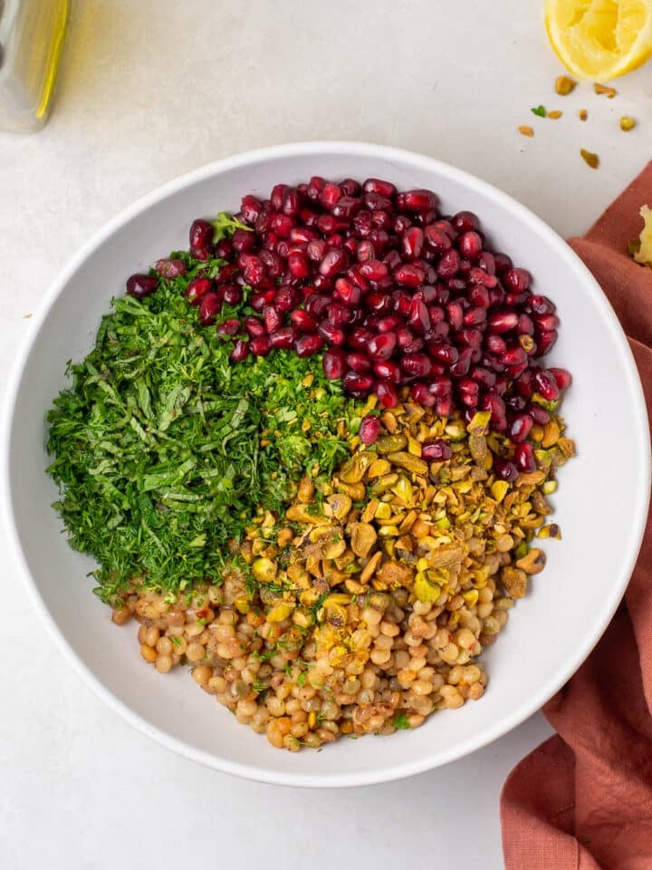 Pearl-shaped pasta with chopped fresh dill, parsley, mint, pistachios and pomegranate added before tossing