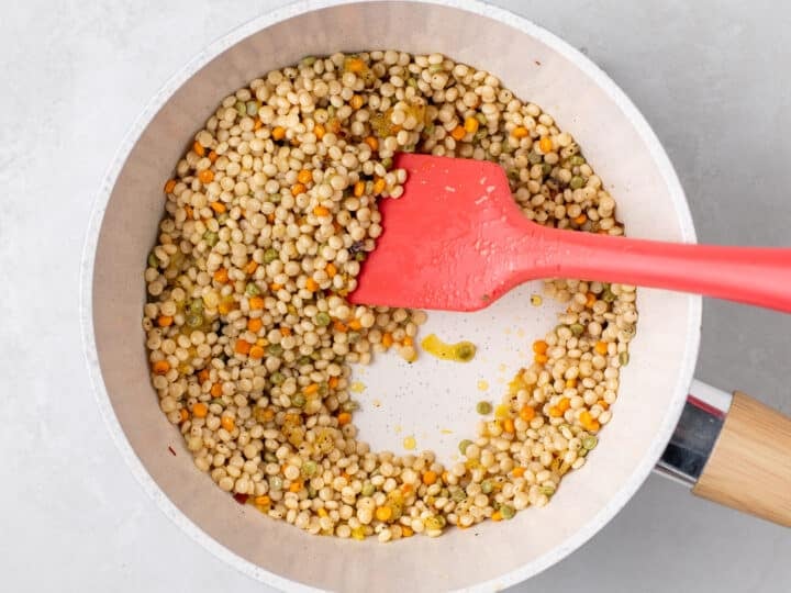 Toasting pearl couscous in olive oil and garlic in saucepan