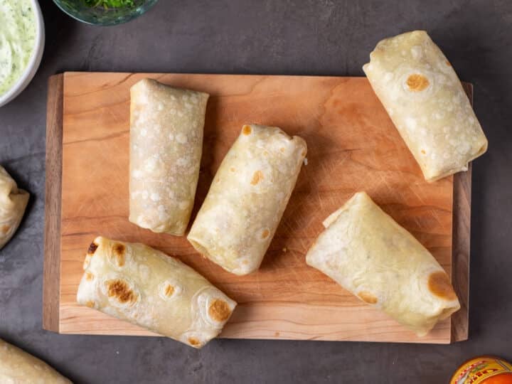 assembled burritos on a wood cutting board