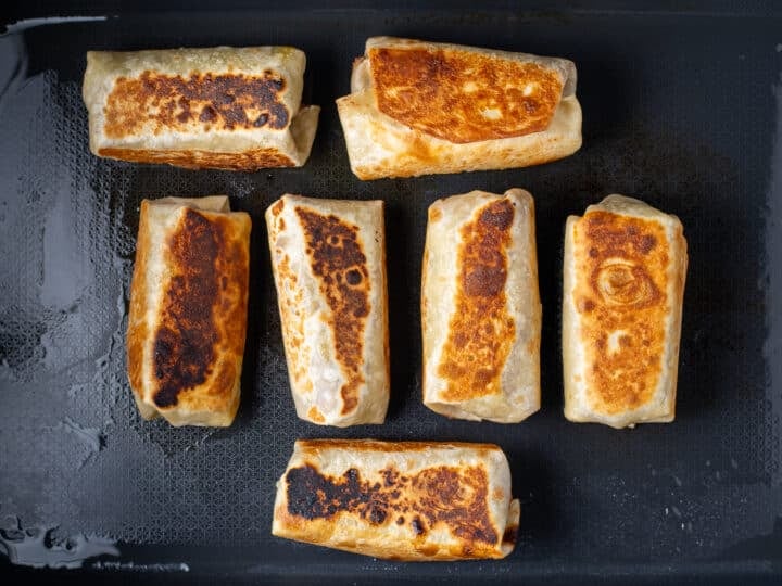 toasted bean and cheese burritos on a black griddle