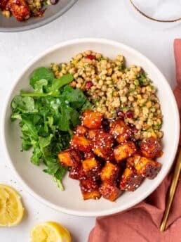 apricot harissa tofu served with couscous pilaf and greens in a Mediterranean-inspired bowl