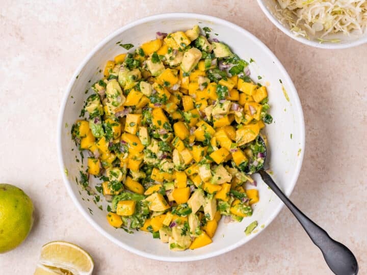 mango and avocado pico de gallo tossed together in a white bowl