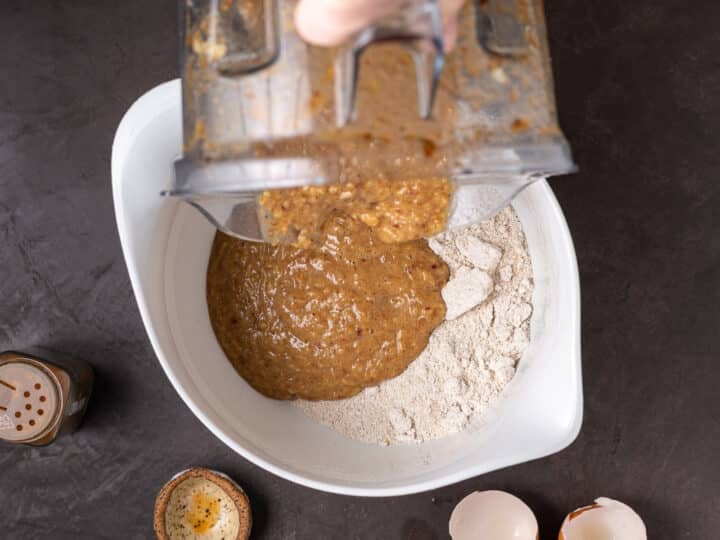 dumping wet ingredients in blender into the oat flour mixture in a bowl