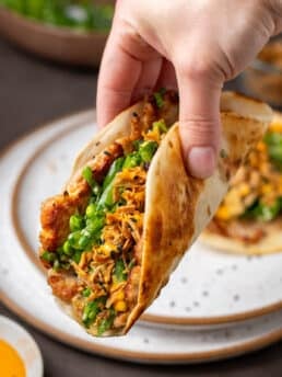 Seared ahi tuna smash taco with snap pea herb salad, crispy shallots, and sriracha mayo in a warm flour tortilla