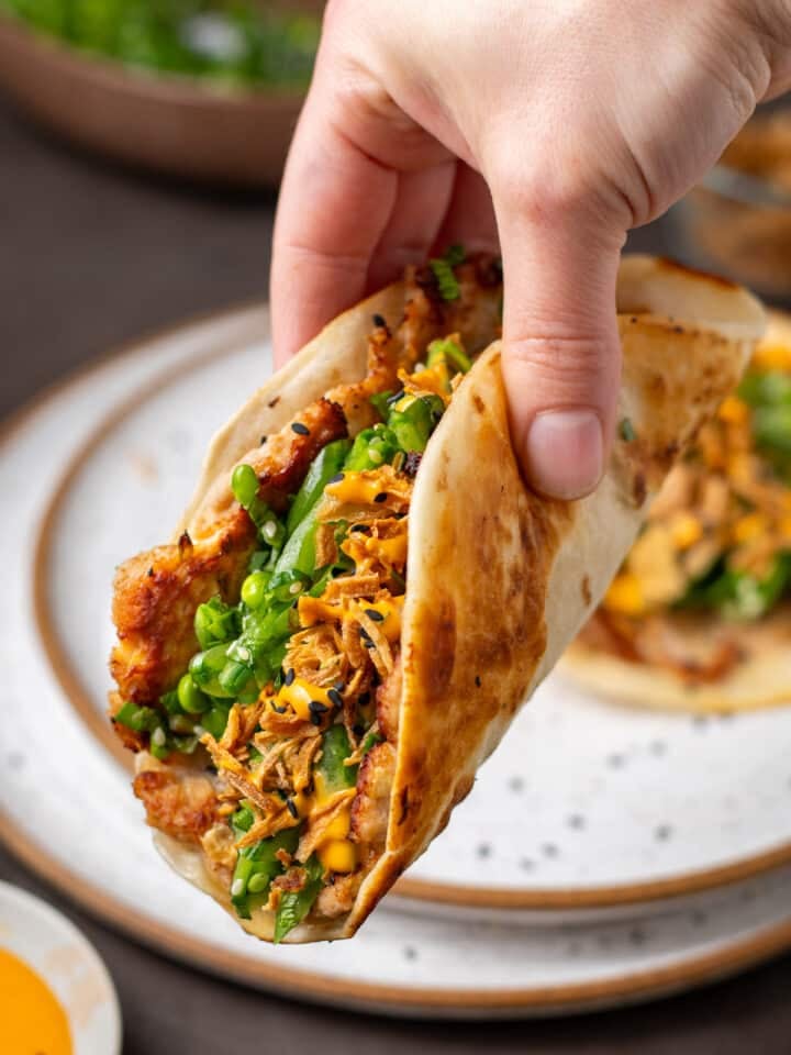 Seared ahi tuna smash taco with snap pea herb salad, crispy shallots, and sriracha mayo in a warm flour tortilla