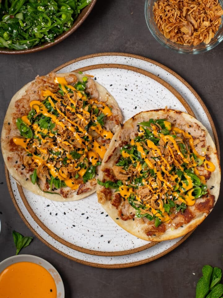 overhead view of two tacos on a white plate - seared ahi tuna tacos with snap pea salad with sriracha mayo drizzle