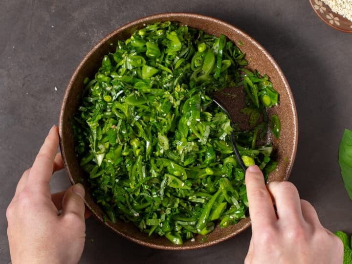 hands stirring together sesame snap pea salad