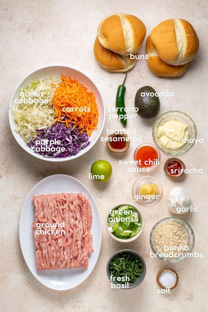 ingredients for sweet chili ground chicken burgers including ground chicken, cabbage, carrots, green onions, garlic, ginger, lime, sesame oil, mayo, sweet chili sauce, sriracha, panko breadcrumbs, basil, avocado, serrano pepper and buns