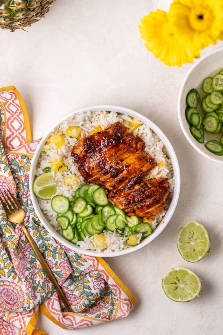 Roasted chili lime chicken thighs served over pineapple coconut rice with pickled cucumbers and fresh lime